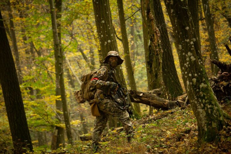 A man in camouflage walking through a forest