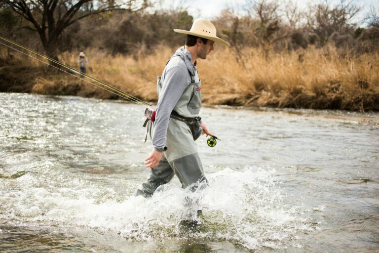 woman in white long sleeve shirt and brown hat holding fishing rod on water during daytime